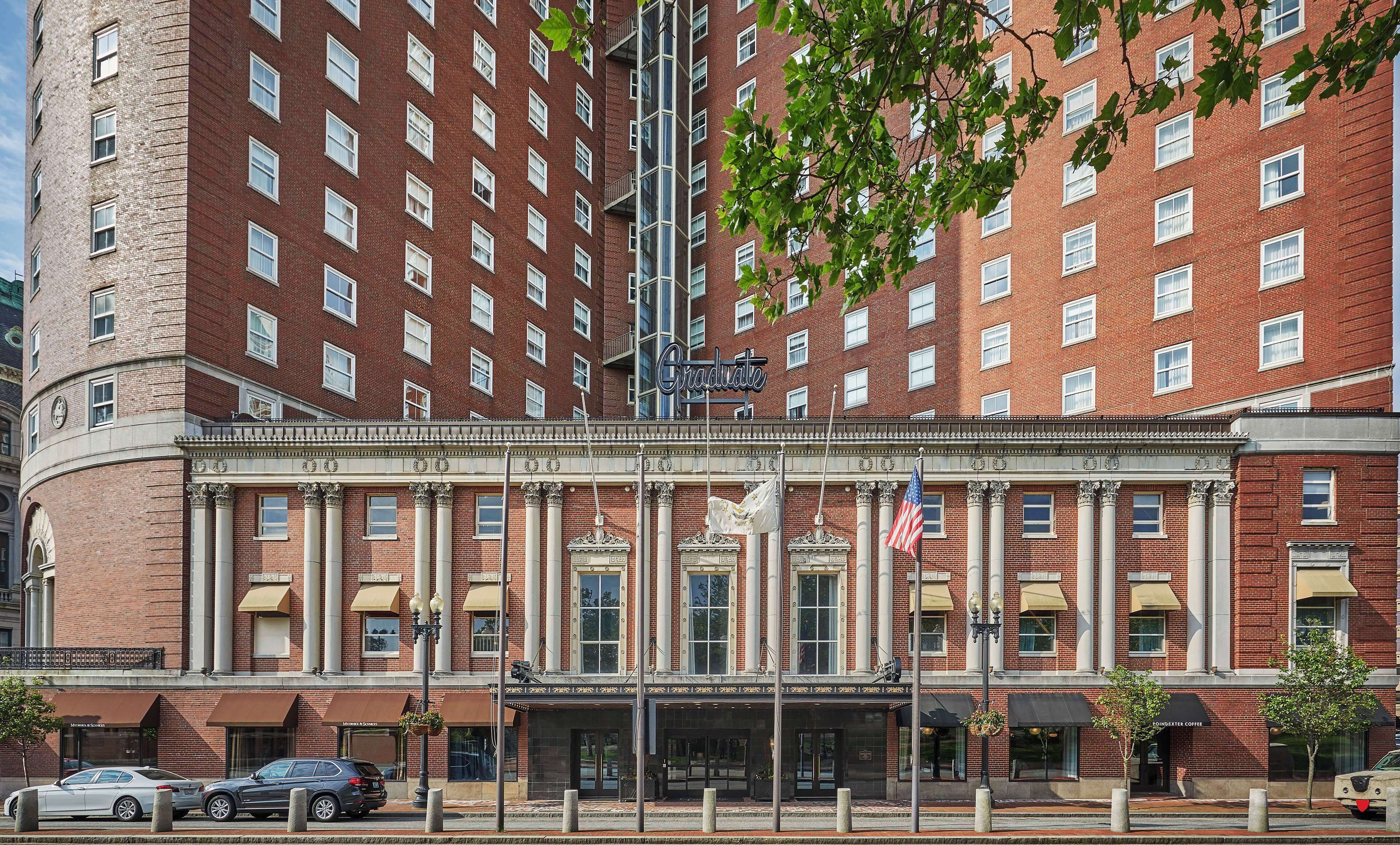 A large brick building with a central entrance, columns, and a flag.