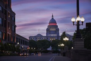 A large government building with a prominent dome, surrounded by trees and street lamps.