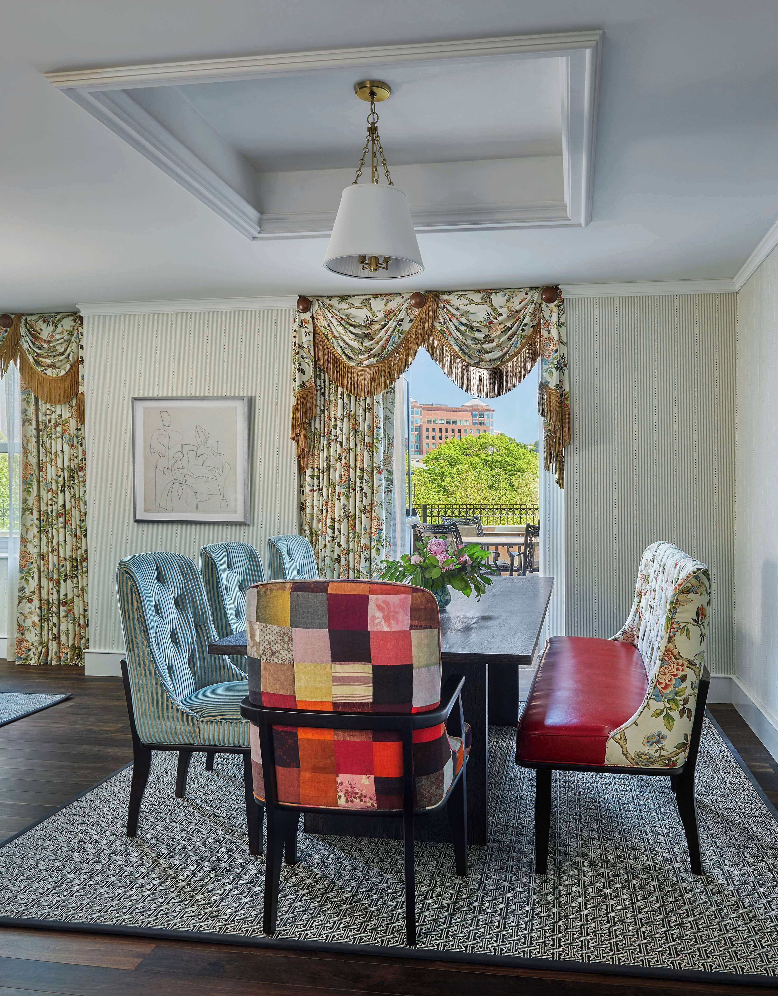 A dining area with a table and chairs, a hanging light fixture, and a view of buildings and trees outside.