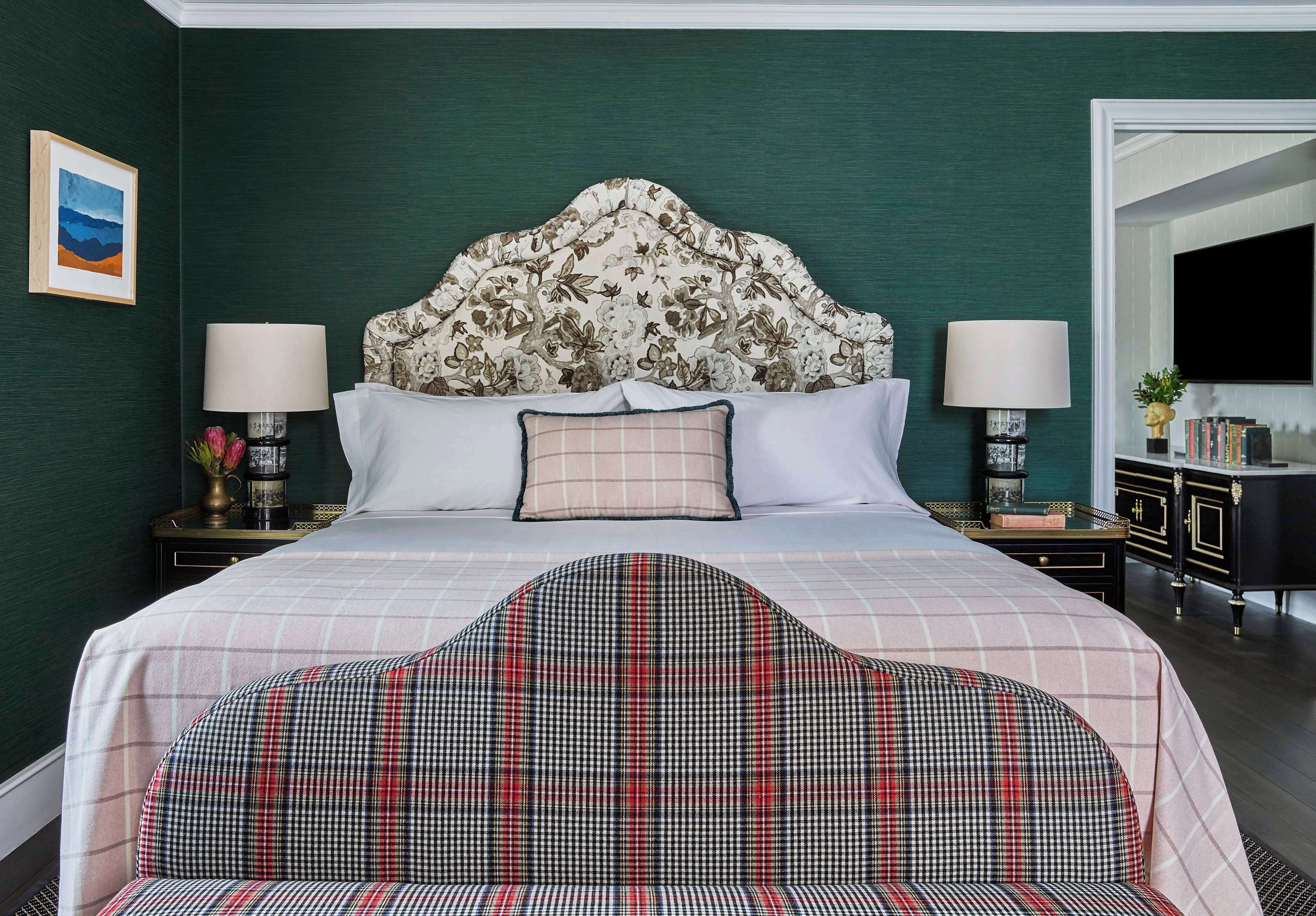 A neatly arranged hotel room with a large bed, two bedside tables, a headboard, and a seating area with a plaid sofa.