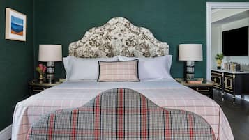 A neatly arranged hotel room with a large bed, two bedside tables, a headboard, and a seating area with a plaid sofa.