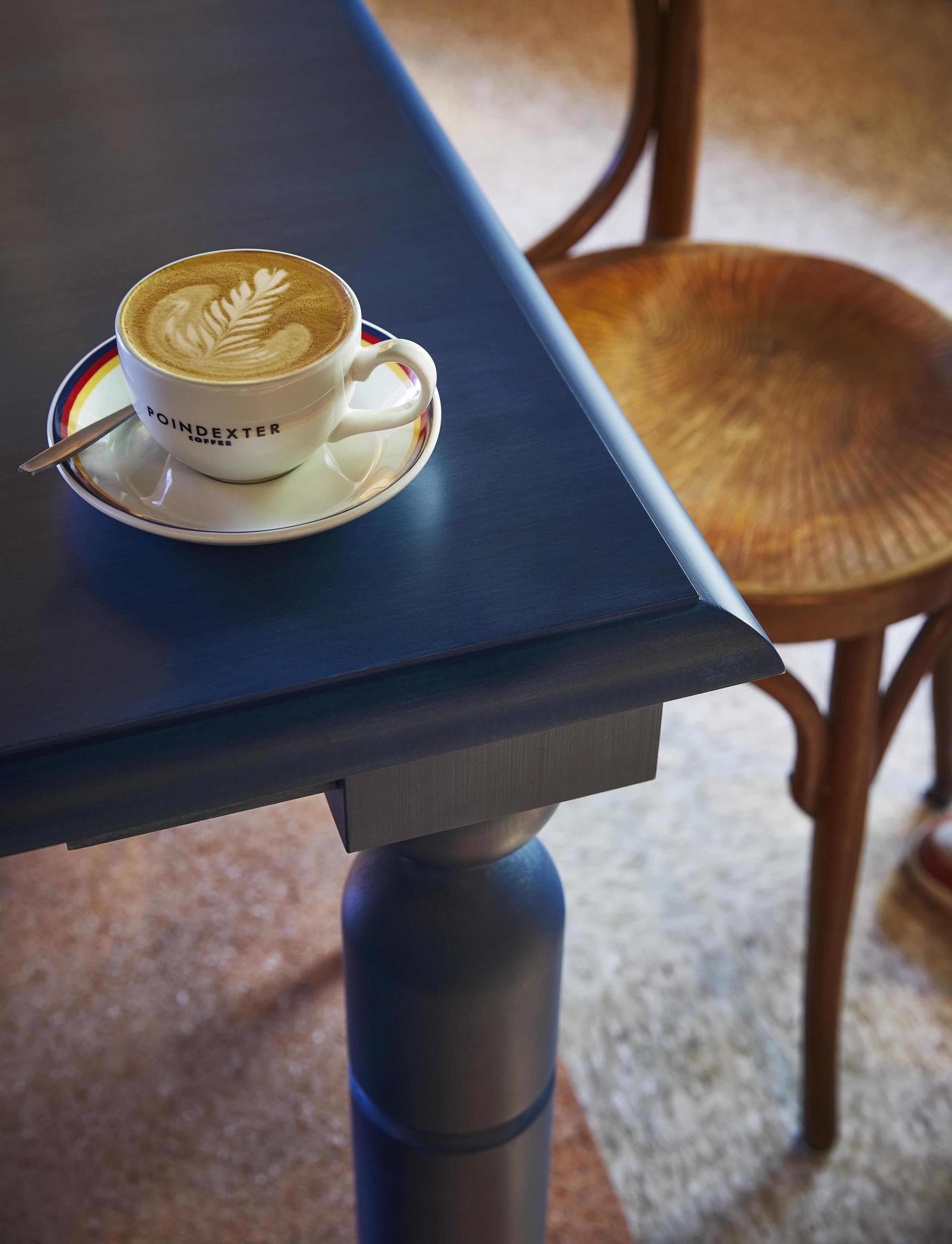Una taza de café con diseño de hoja en la espuma, con el texto 