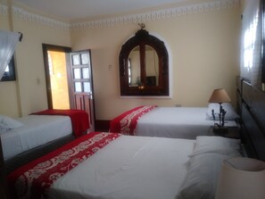 Une chambre d’hôtel avec deux lits simples, un grand miroir, une lampe de chevet et une fenêtre avec des rideaux.