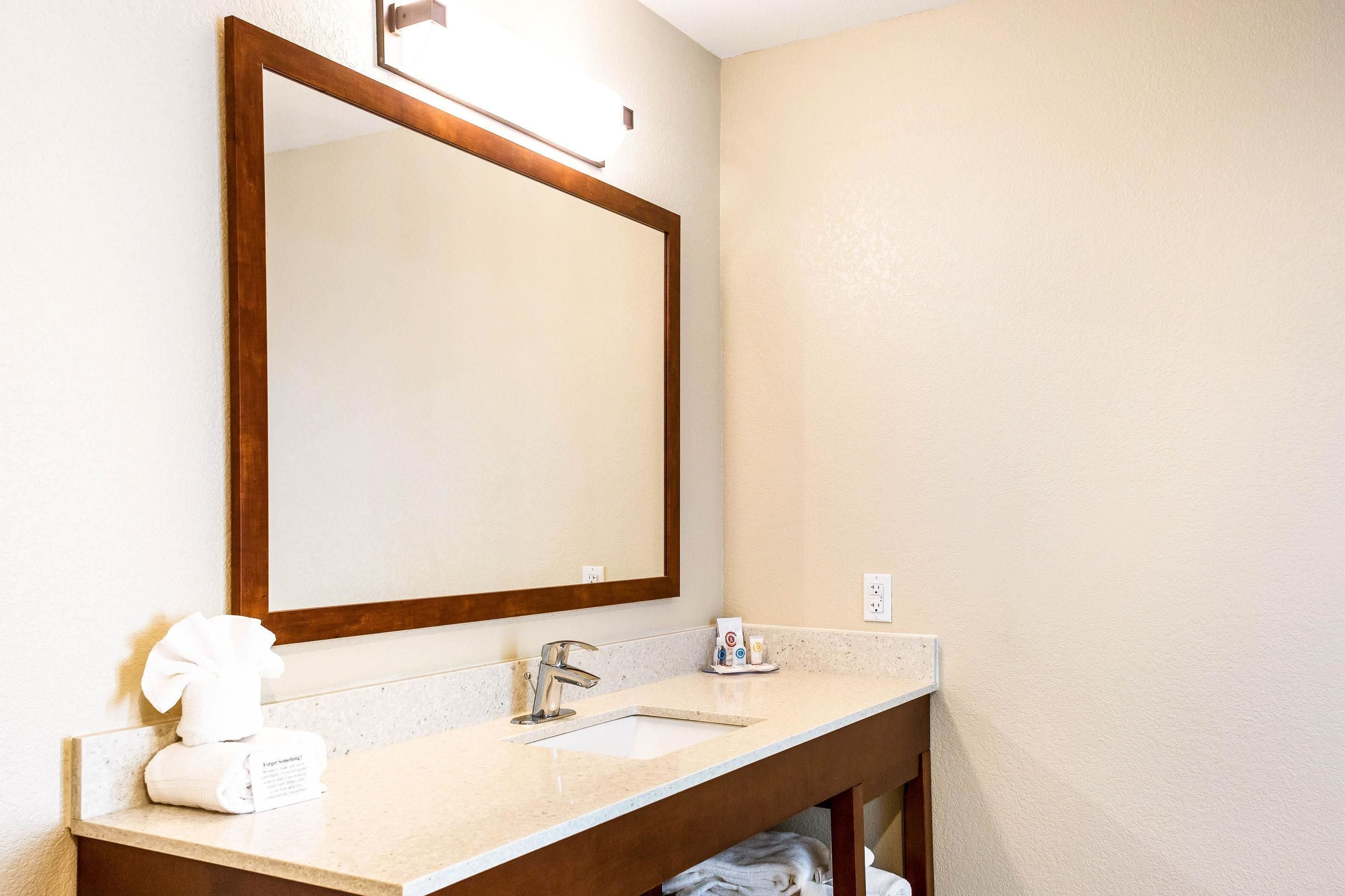 Un baño con un espejo grande, un lavabo y un perchero para toallas.