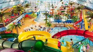 Un parque acuático con toboganes, piscinas y palmeras.