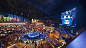 Un espacio interior amplio con una zona de asientos circular central, varios mostradores y una pantalla grande que muestra contenido.
