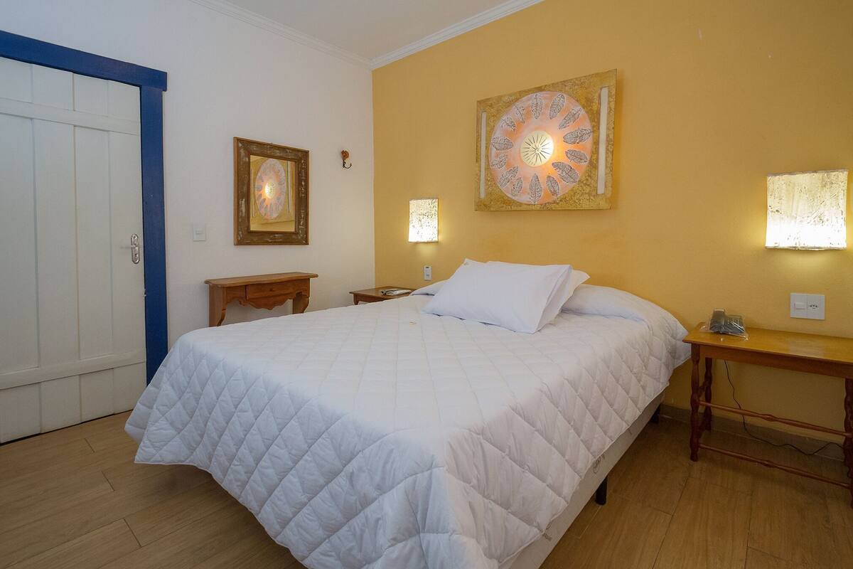 A bedroom with a bed, a nightstand, a wall clock, and a door.