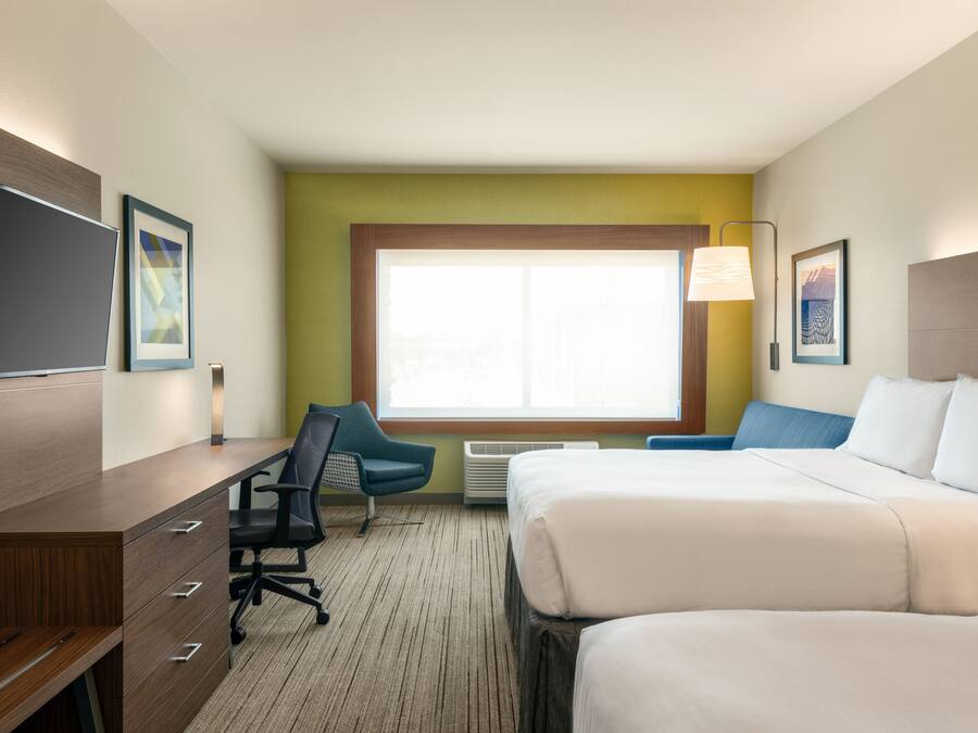 A hotel room with a bed, a desk with a chair, a television, and a window with a view.