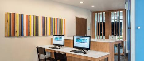 Una mesa de recepción con dos monitores de computadora, una superficie de madera y una silla.