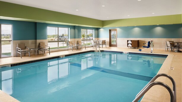 A swimming pool with clear blue water, surrounded by lounge chairs and a wooden cabinet. - Holiday Inn Express & Suites West Des Moines - Jordan Creek by IHG (West Des Moines)