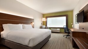 A hotel room with a large bed, a desk with a chair, a flat-screen TV, a window with blinds, and a wall-mounted lamp. - Holiday Inn Express & Suites West Des Moines - Jordan Creek by IHG (West Des Moines)