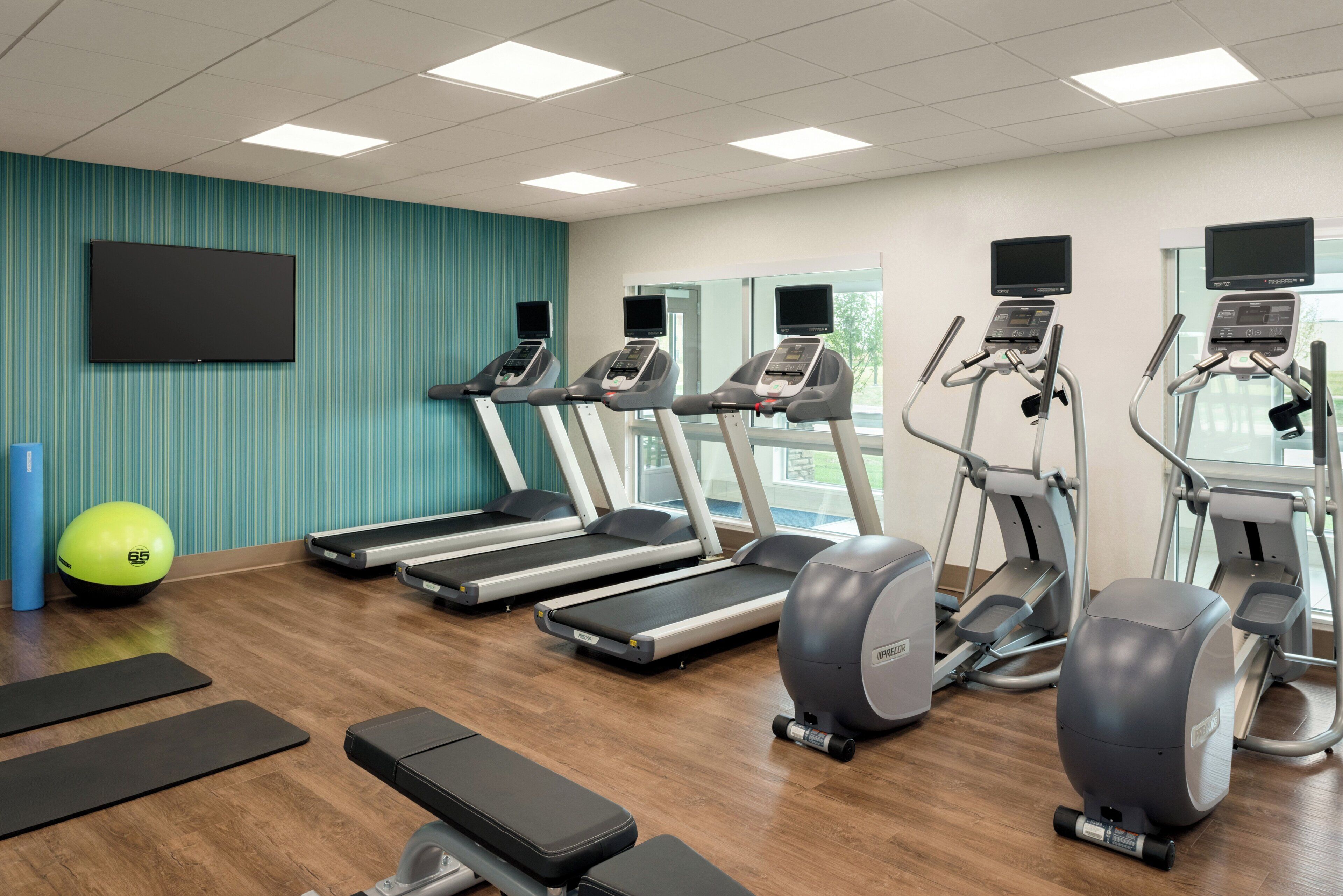 Een fitnessruimte met loopbanden, elliptische trainers, een hometrainer en een roeimachine.