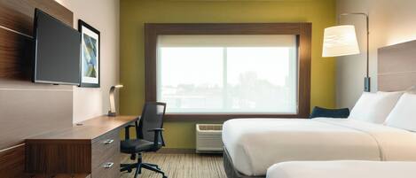 A hotel room with a bed, a desk with a chair, a TV, and a window with a city view.