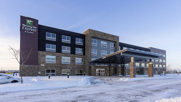 A Holiday Inn Express & Suites building with a modern design, featuring a stone facade and a covered entrance. - Holiday Inn Express & Suites West Des Moines - Jordan Creek by IHG (West Des Moines)