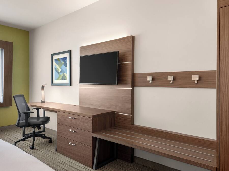 Habitación de hotel con escritorio de madera, televisor de pantalla plana, un cuadro enmarcado y una ventana.