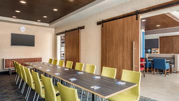 A conference room with a long table, yellow chairs, and a clock on the wall.