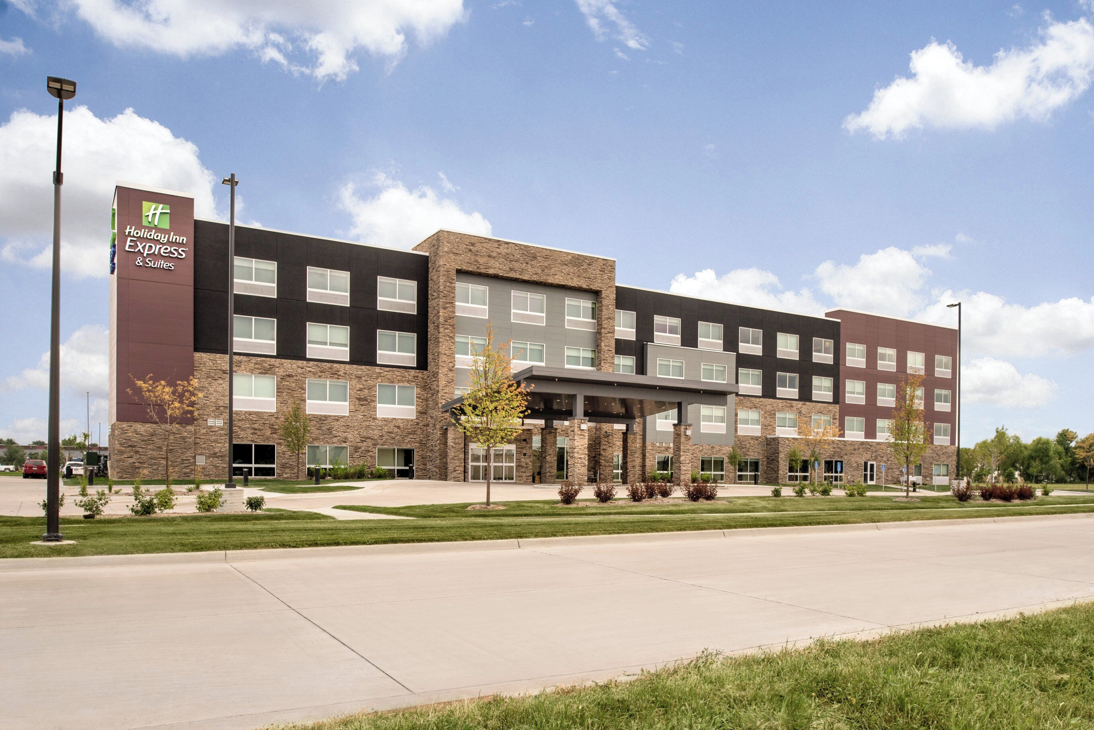 A Holiday Inn Express & Suites hotel with a modern design, featuring a stone facade and multiple windows.