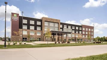 A Holiday Inn Express & Suites hotel with a modern design, featuring a stone facade and multiple windows.