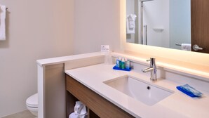 Une salle de bain moderne avec un lavabo blanc, un miroir au-dessus et un porte-serviettes fixé au mur.