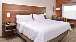 Une chambre d’hôtel avec un grand lit, une table de chevet avec un téléphone, une chaise et une fenêtre donnant sur un beau paysage.