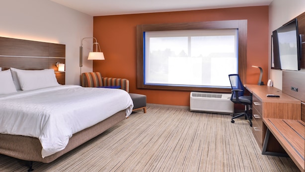 Une chambre d’hôtel avec un lit, un bureau, une chaise, une télévision et une grande fenêtre.