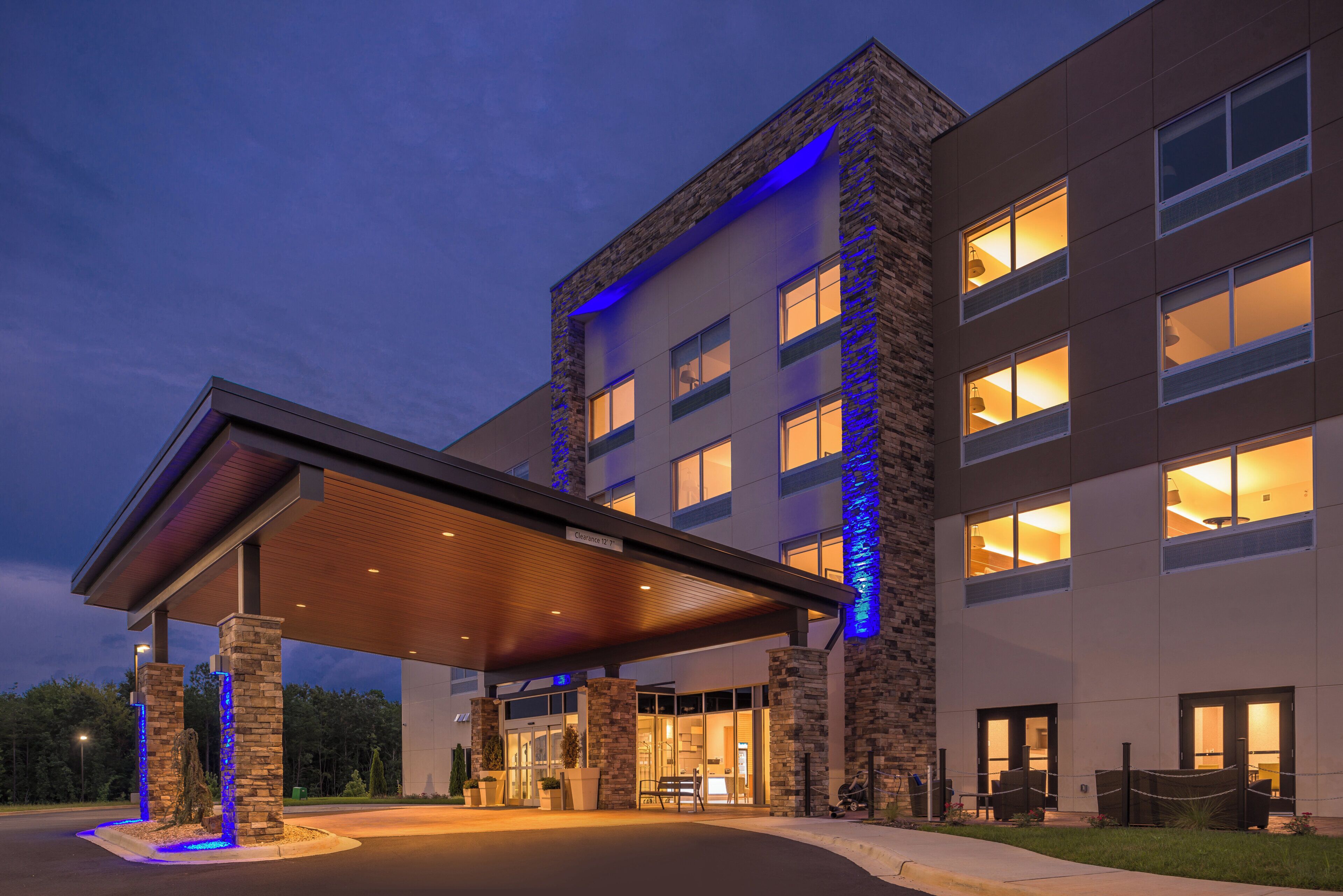 A hotel entrance with a covered driveway, stone facade, and illuminated windows.