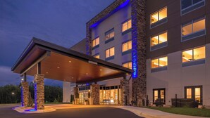 A hotel entrance with a covered driveway, stone facade, and illuminated windows.