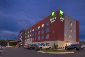 Ein Holiday Inn Express & Suites Hotel mit modernem Design, mehreren Parkplätzen und blauem Himmel.