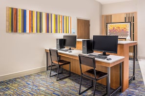 Un espace de travail comprenant deux bureaux, chacun équipé d’un écran d’ordinateur, d’un clavier et d’une souris. On y trouve également deux chaises, une moquette à motifs et un mur recouvert de lambris en bois verticaux.