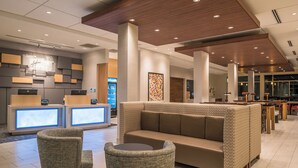 A modern lobby with a reception desk, seating area, and a coffee station.
