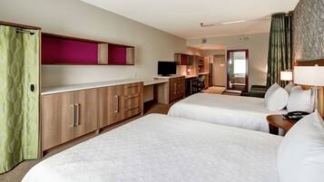 A hotel room with two beds, a TV, a desk, and a mirror.