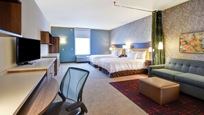 A hotel room with a desk, two beds, a sofa, a TV, and a large window. - Home2 Suites by Hilton Springfield North (Springfield)