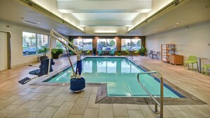 An indoor swimming pool with a lifeguard chair, poolside chairs, and a view of the parking lot outside. - Home2 Suites by Hilton Springfield North (Springfield)