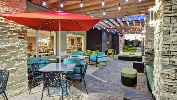 An outdoor patio area with stone walls, wooden beams, and string lights.