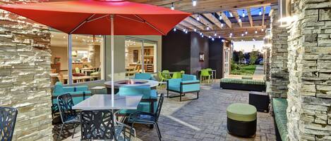 An outdoor patio area with stone walls, wooden beams, and string lights.