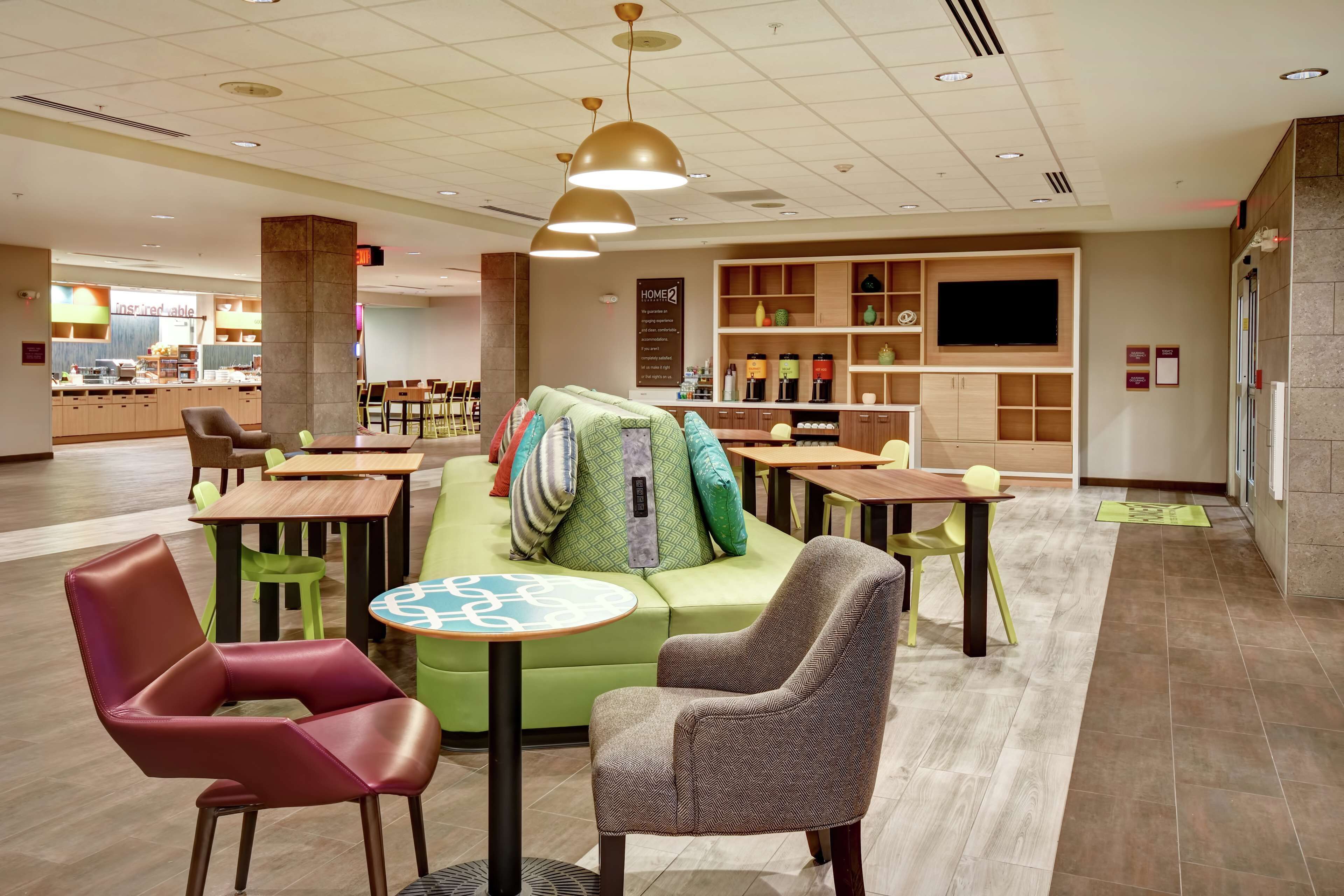 A modern lounge area with seating, a coffee station, and a TV screen.