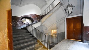 Un escalier avec une rampe en métal, une porte en bois et une lanterne suspendue.