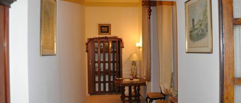 Um corredor com um armário de madeira, uma mesa com abajur e uma cadeira.