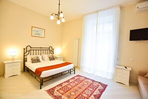 A bedroom with a bed, bedside tables, a TV, and a window with curtains. - Domus Borbonica (Naples)