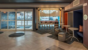 A modern lobby with a reception desk, seating area, and glass doors leading outside. - Tru by Hilton Garland Richardson (Garland)