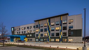 A modern hotel with a multi-story structure, a parking lot, and a blue entrance canopy. - Tru by Hilton Garland Richardson (Garland)