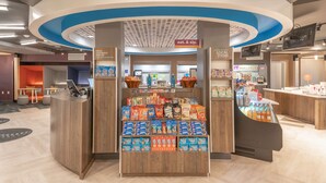 A 24/7 market area with snacks, beverages, and a cash register. - Tru by Hilton Garland Richardson (Garland)
