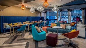 A modern lounge area with seating arrangements, tables, and hanging pendant lights. - Tru by Hilton Garland Richardson (Garland)