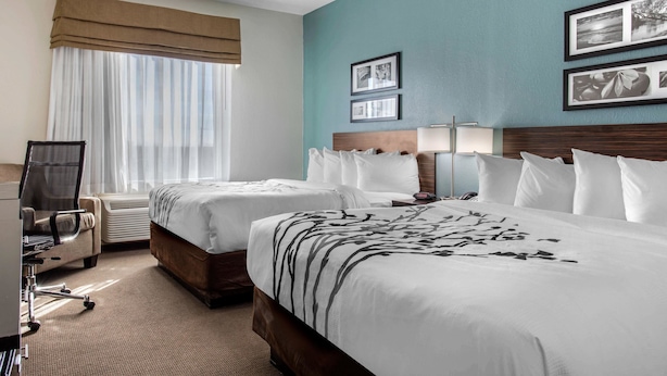 A hotel room with two beds, a desk, a chair, and a window with curtains. - Sleep Inn Big Spring North I-20 (Big Spring)
