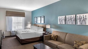 A hotel room with a bed, a sofa, a coffee table, and wall art.