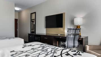 A hotel room with two beds, a desk, a chair, a television, and a lamp.