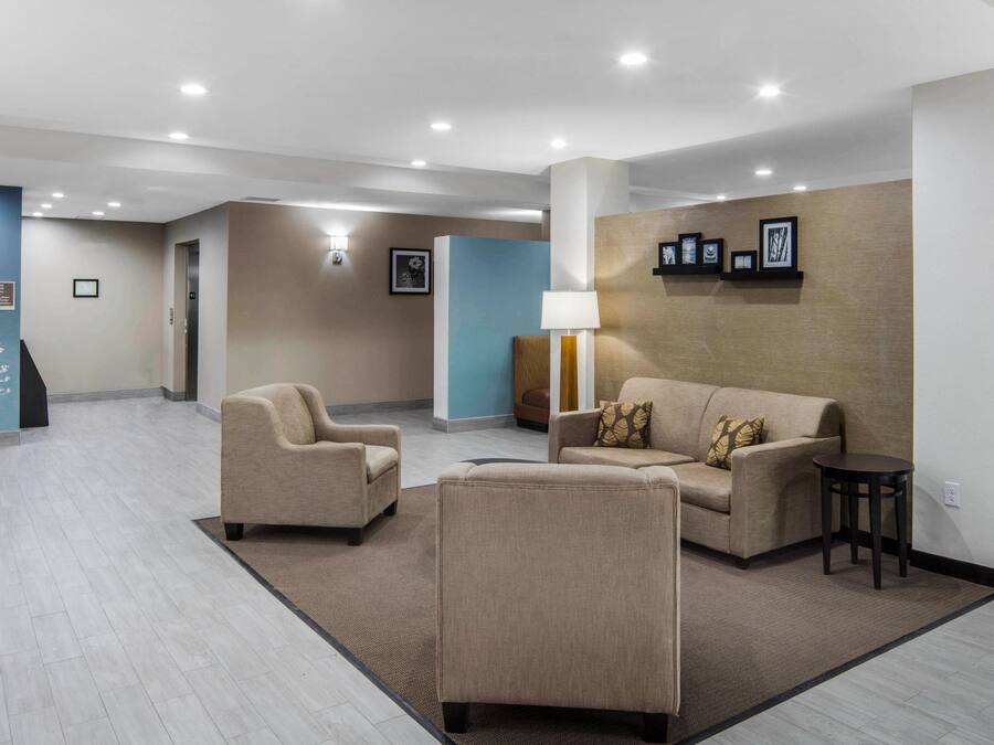 A spacious lobby with a beige sofa, two armchairs, a small table, and a lamp.