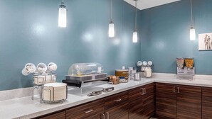 A breakfast bar with a buffet setup, including a coffee machine, cereal, and condiments.
