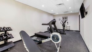 A gym with exercise equipment including a treadmill, stationary bike, and dumbbells.