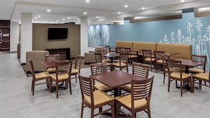 A modern hotel lobby with multiple seating areas, including tables and chairs, a sofa, and a flat-screen TV mounted on the wall. - Sleep Inn Big Spring North I-20 (Big Spring)